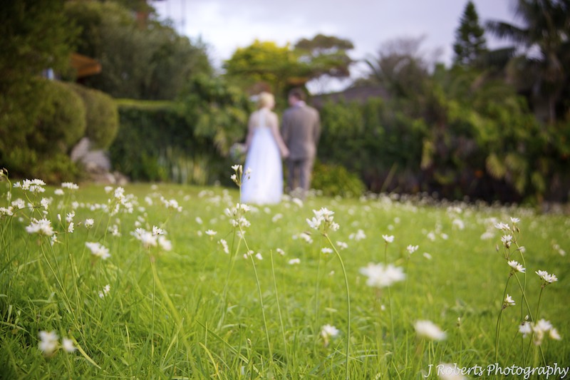 Bride and groom walking through white flowers - wedding photography sydney